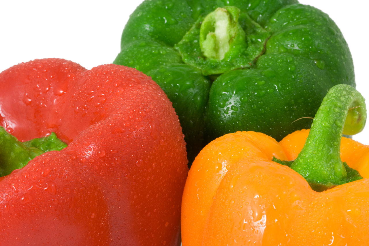 Red green and yellow peppers with water drops