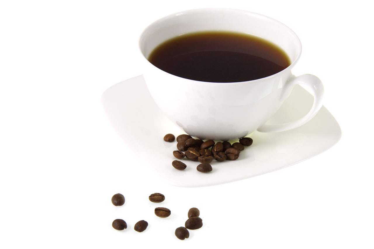 A cup of coffee on white background with several coffee beans