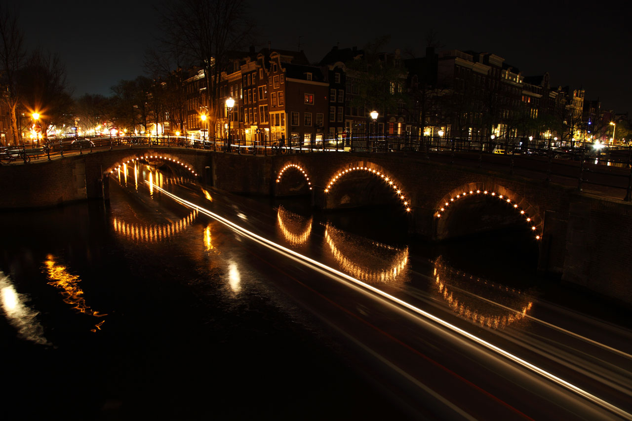 Illuminated bridges with passing boat at night in Amsterdam