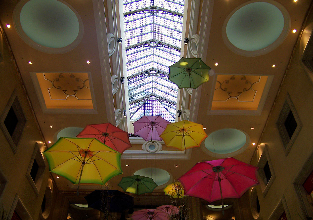 Picture taken of lots of differant colored umbrellas hanging from a ceiling.
