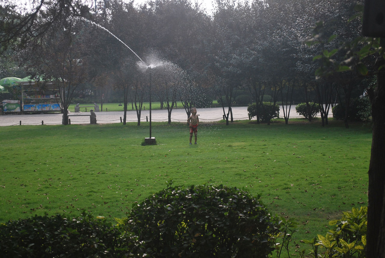 a young boy cools off under a sprinkler