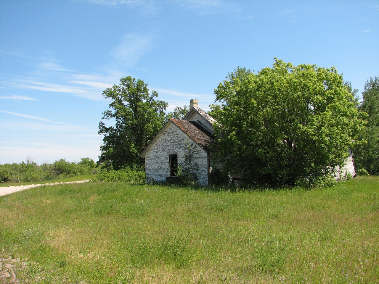 Old country farm building with blue sky and green fields