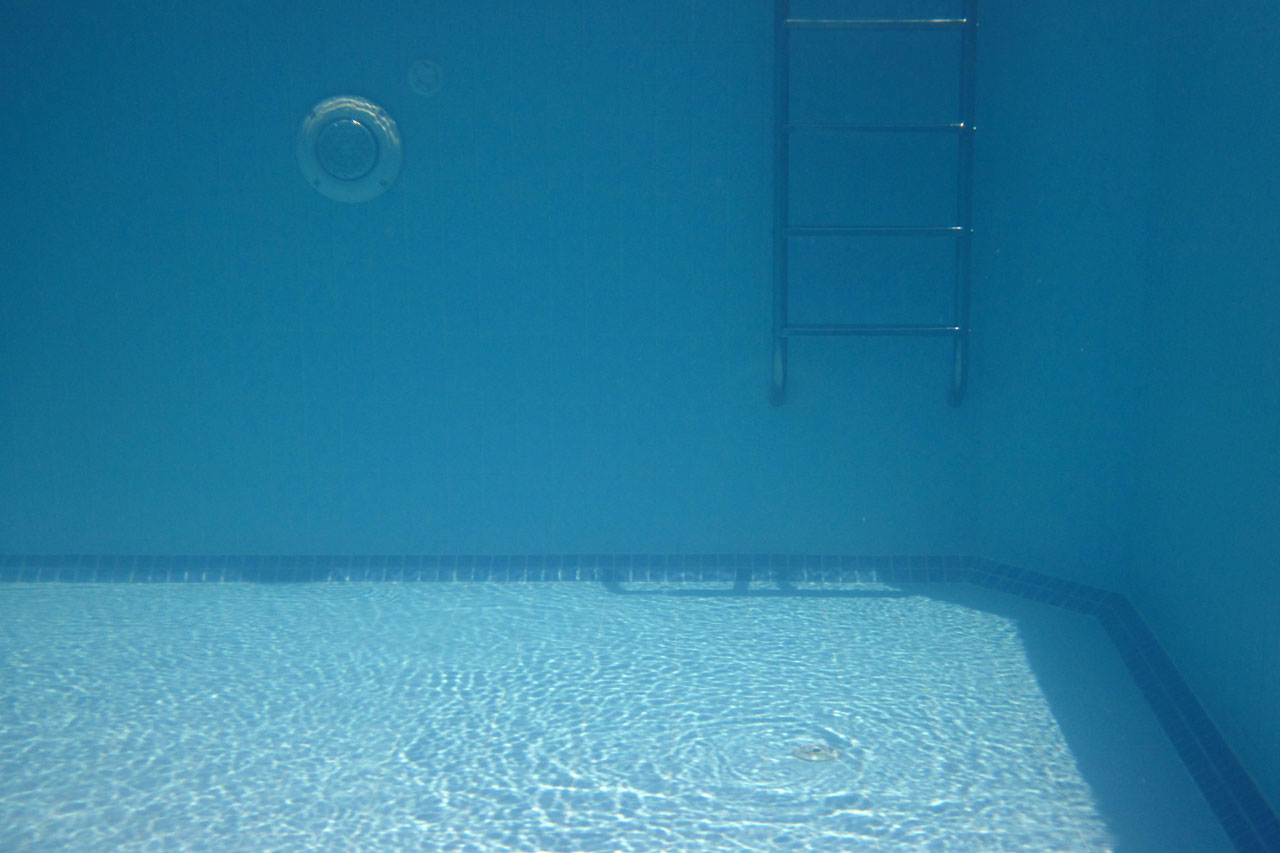 blue swimming pool underwater with ladder