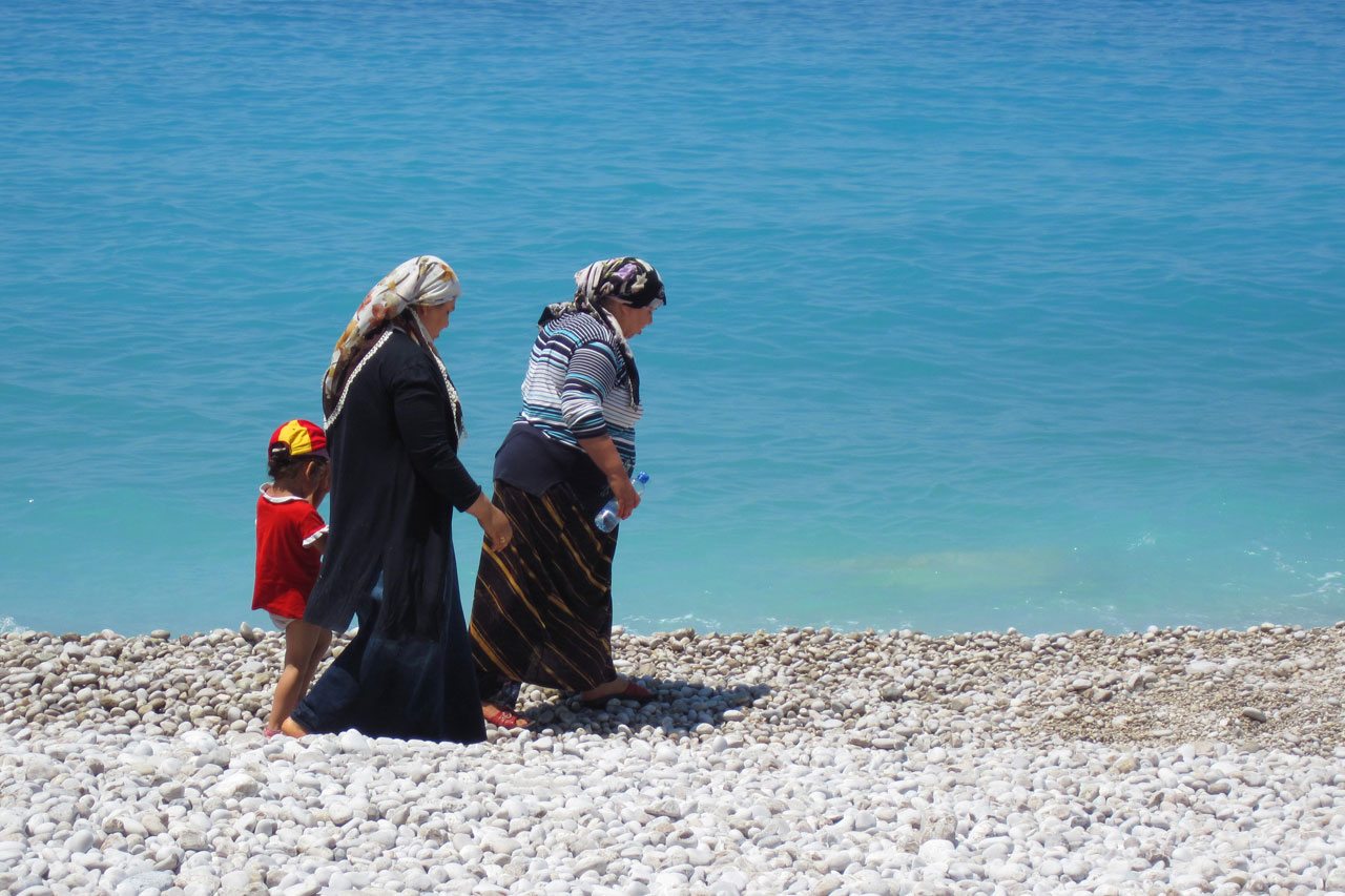 older turkish women in traditional clothes walking on beach