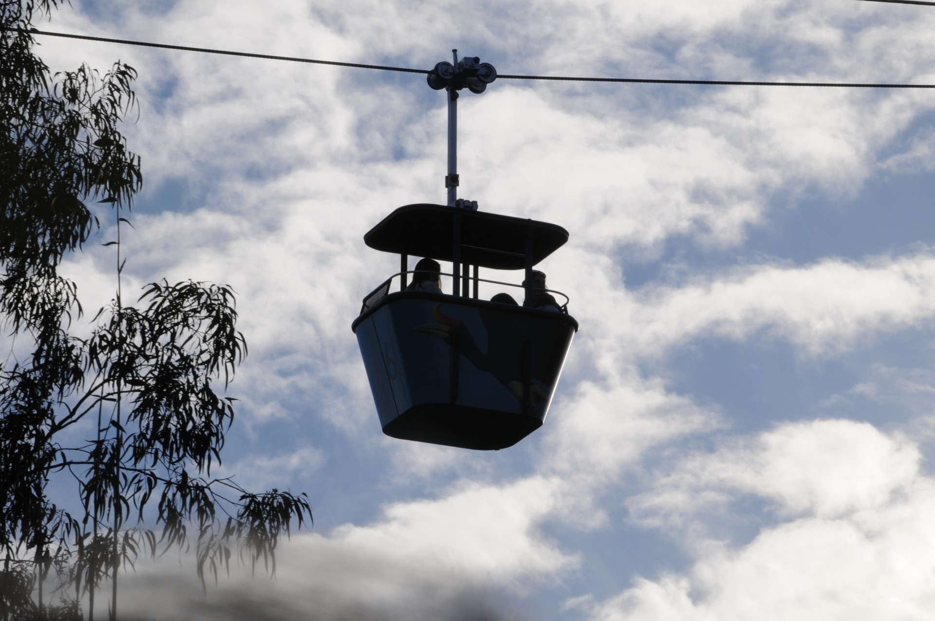 Aerial Tramway car silhouetted against bright blue sky and white clouds