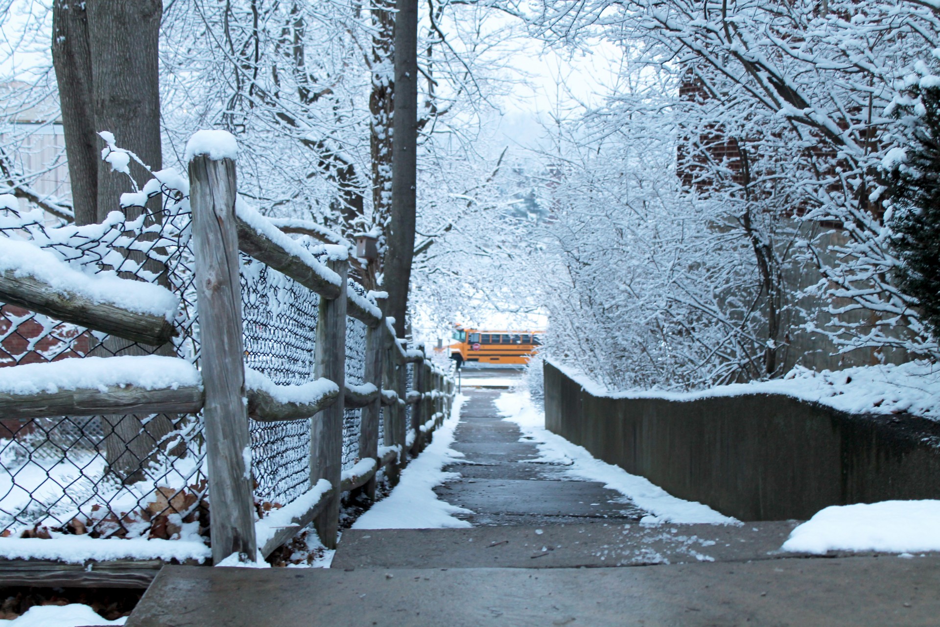 Snow Covered Fence With School Bus In Winter