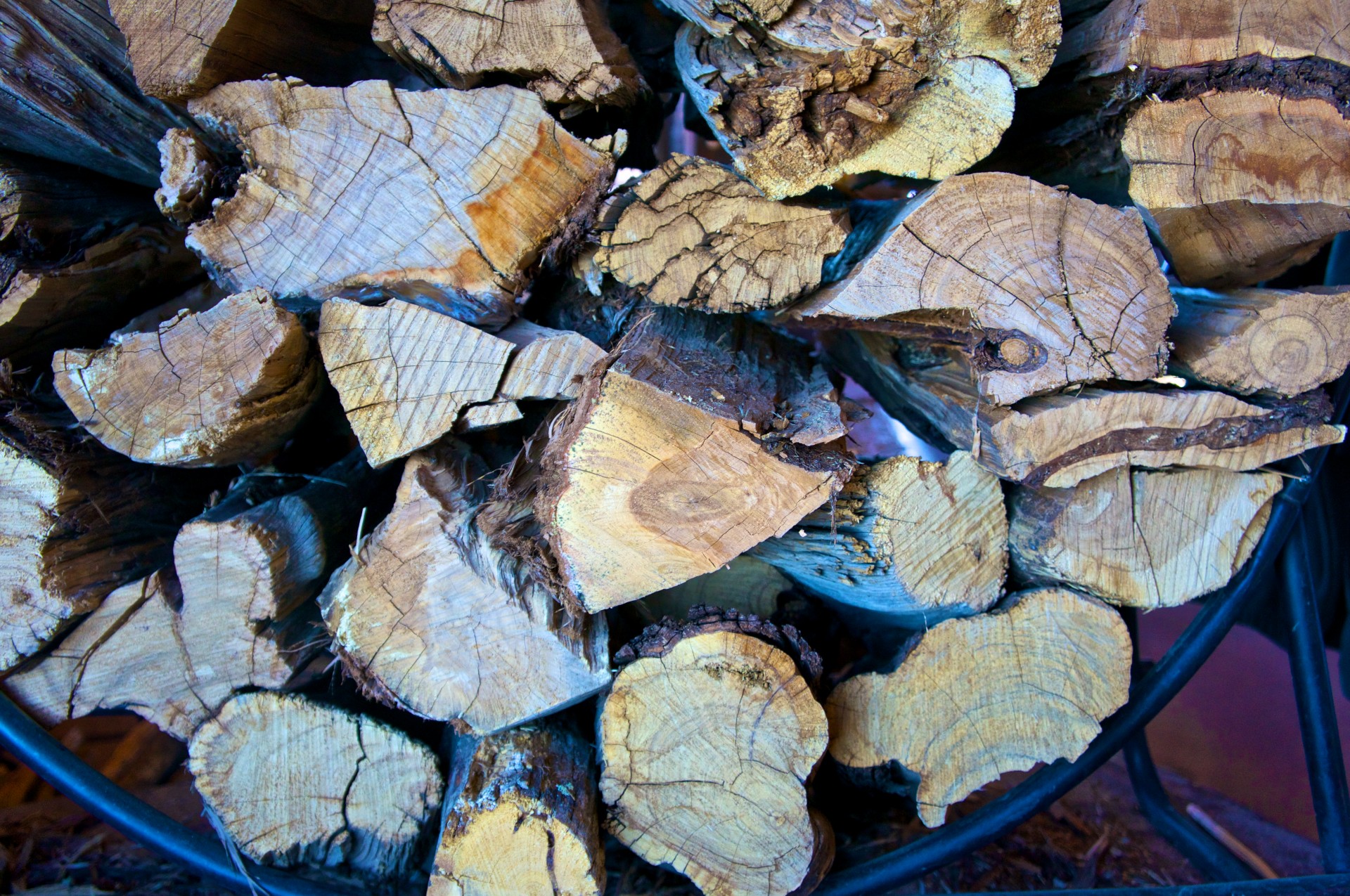 Cord of firewood stacked on an iron rail.