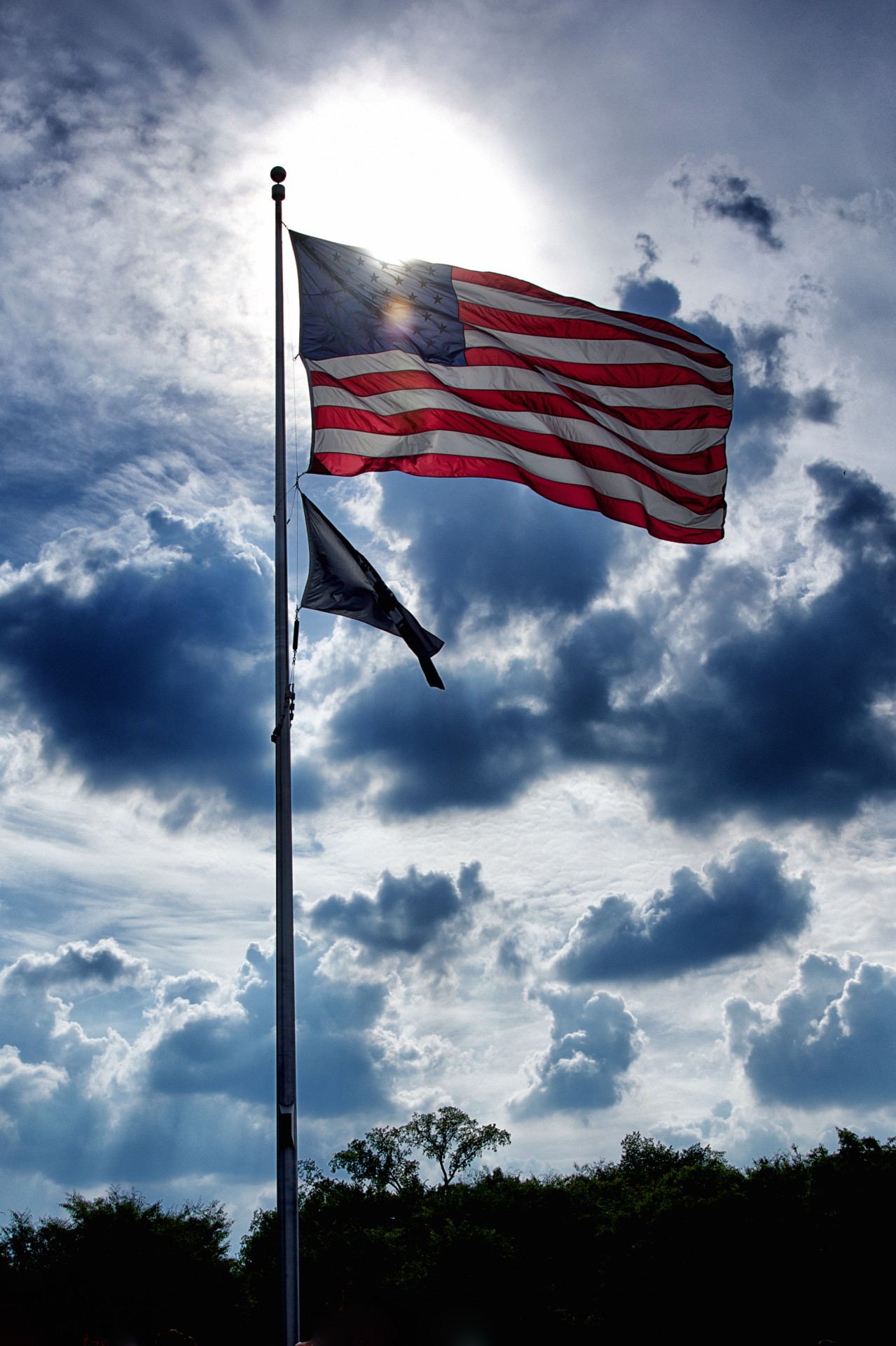 Sun light shines between clouds illuminating an American flag in Washington DC.