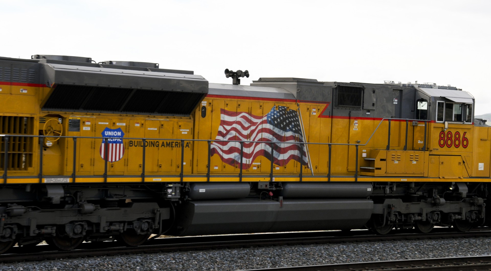 Bright yellow Union Pacific Train car with a proud American Flag painted on it passes through the Palm Springs Desert landscape