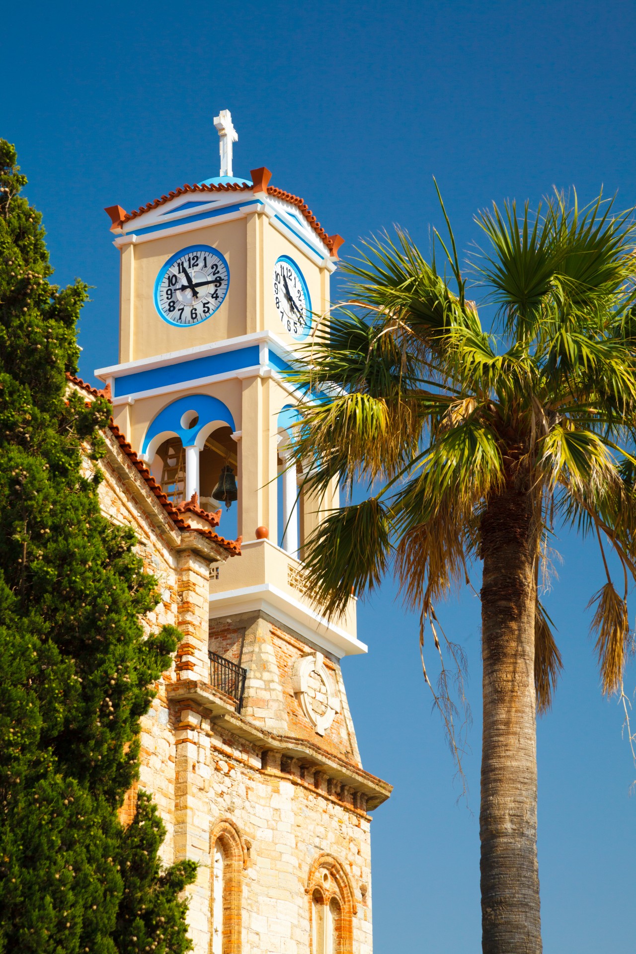 Greek church with a palm tree and blue sky