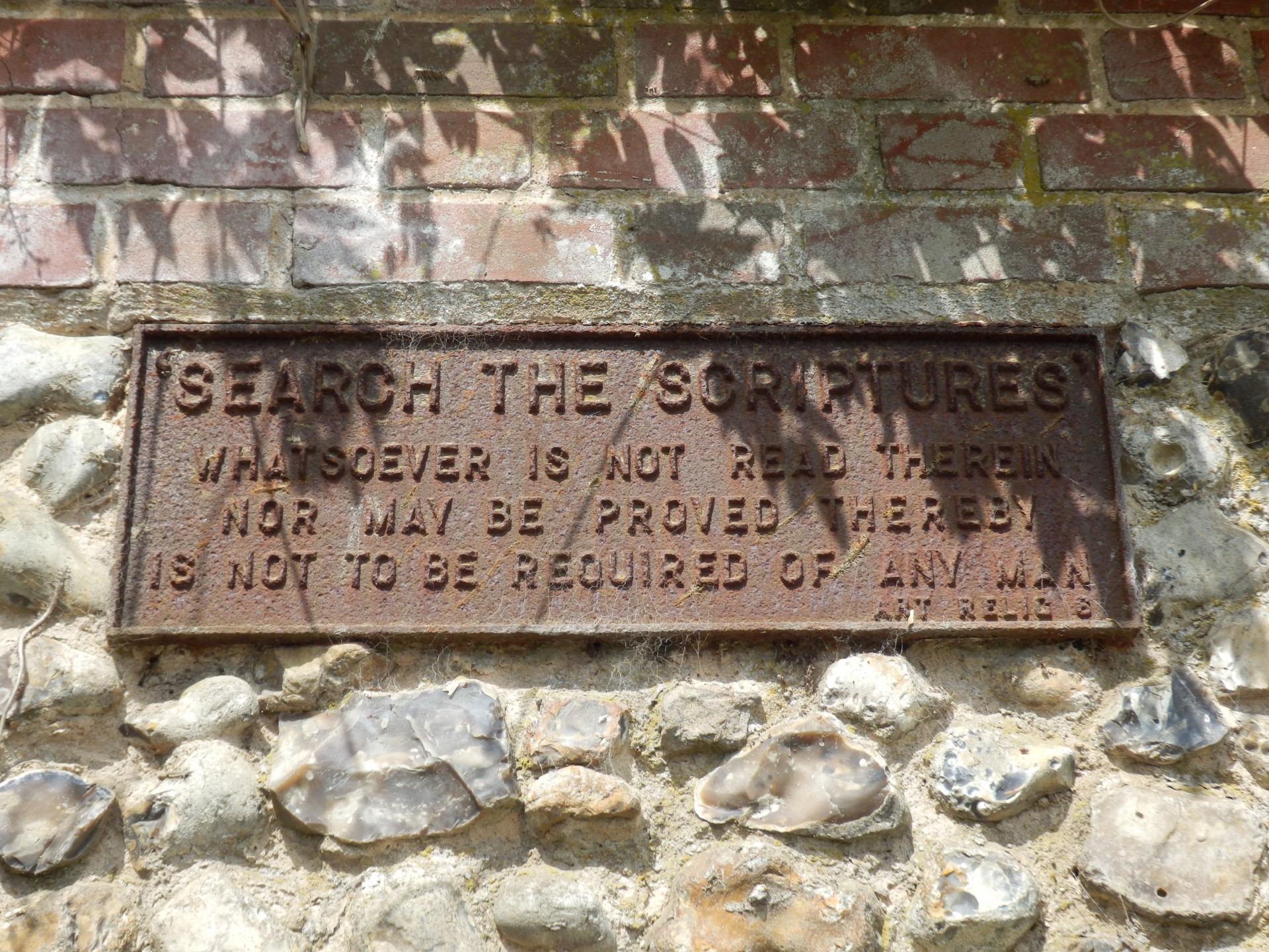 An old sign in a stone wall about reading the Scriptures (Bible).