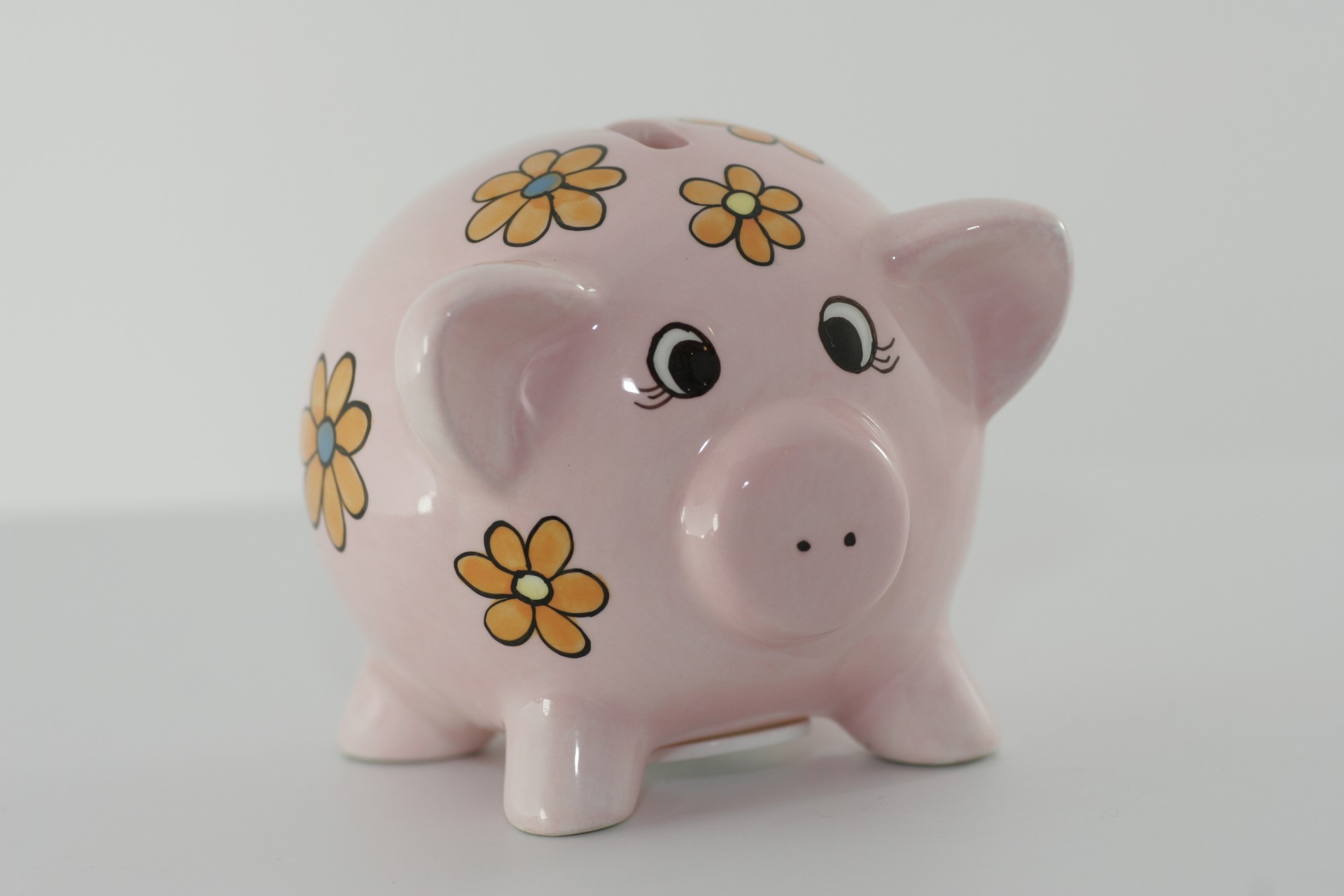 Small pink pig piggy bank for putting with orange flowers for small coins and change.