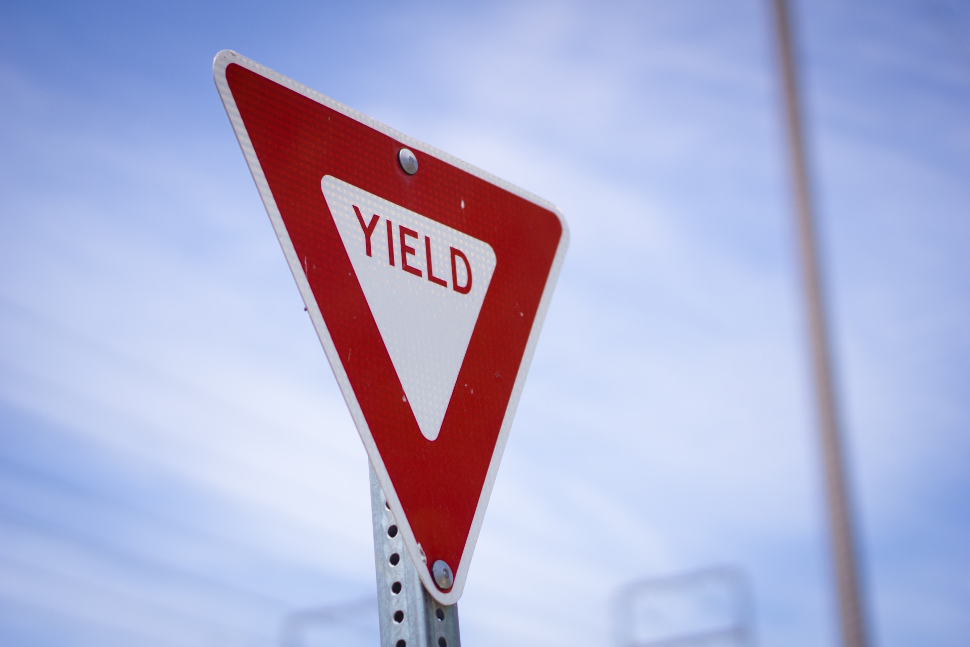 Red and white Yield Road sign long a street.