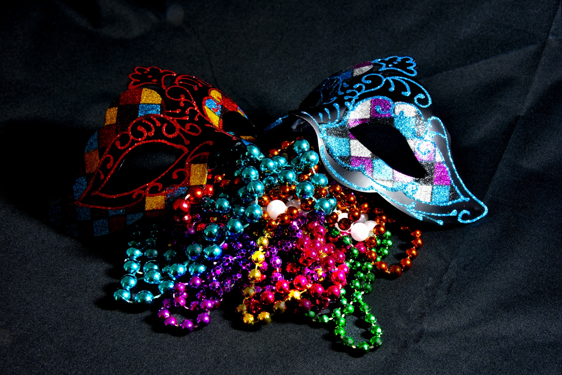 Carnival mask and Mardi Gras beads on a black background