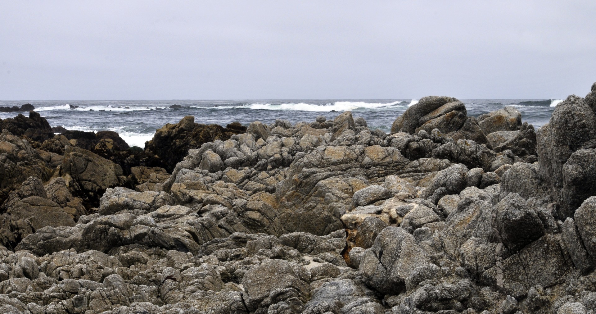 View of the ocean waves from the top of a rocky shoreline at Asilomar State Beach, California