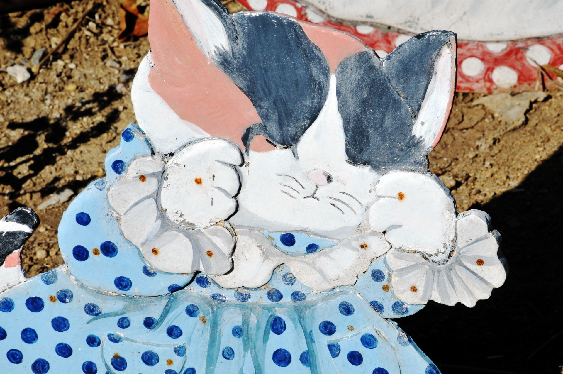 Cute lawn decoration of a calico kitty wearing a blue polka dot dress