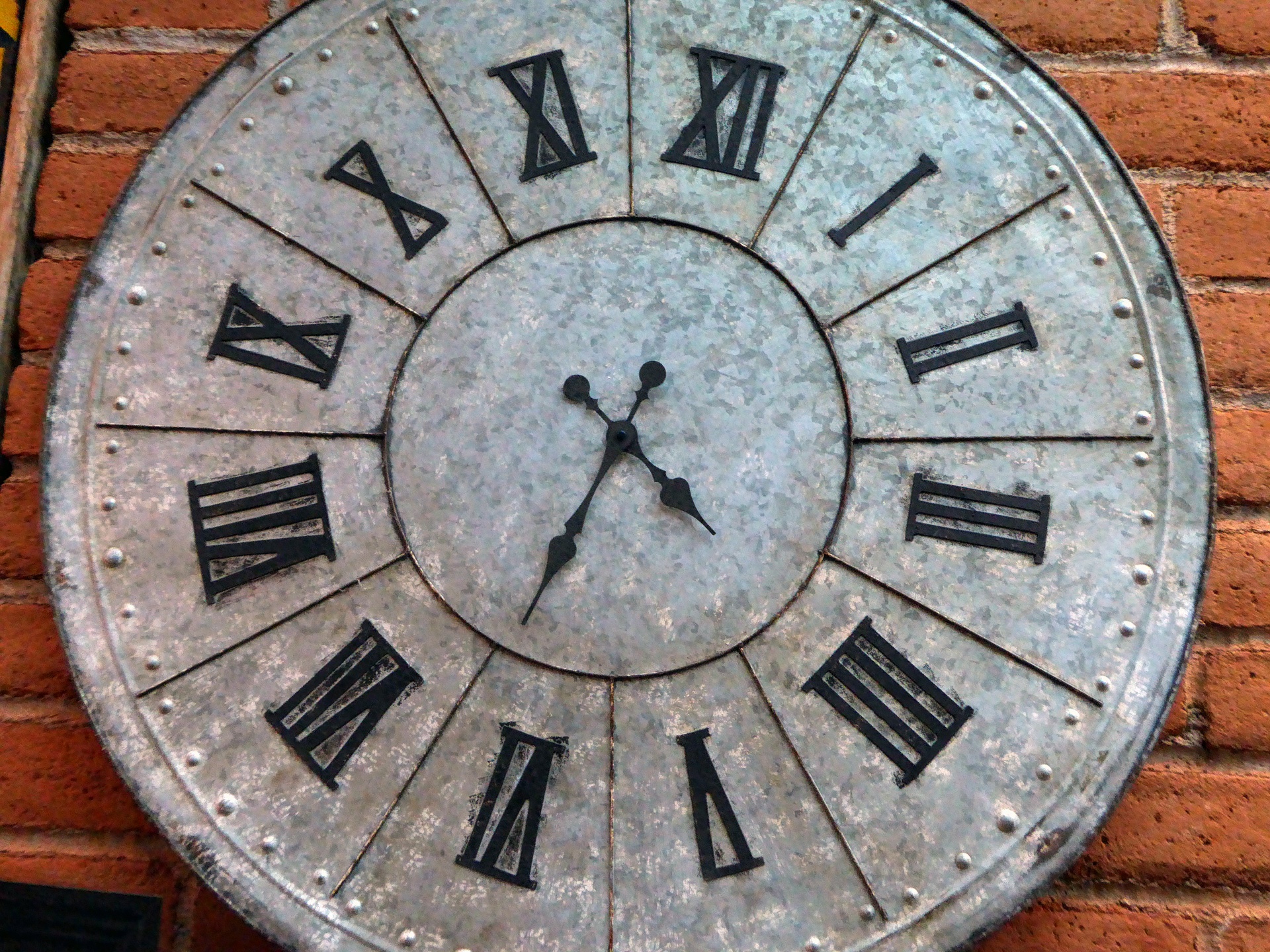 Close up of a metal wall clock with roman numeral numbers
