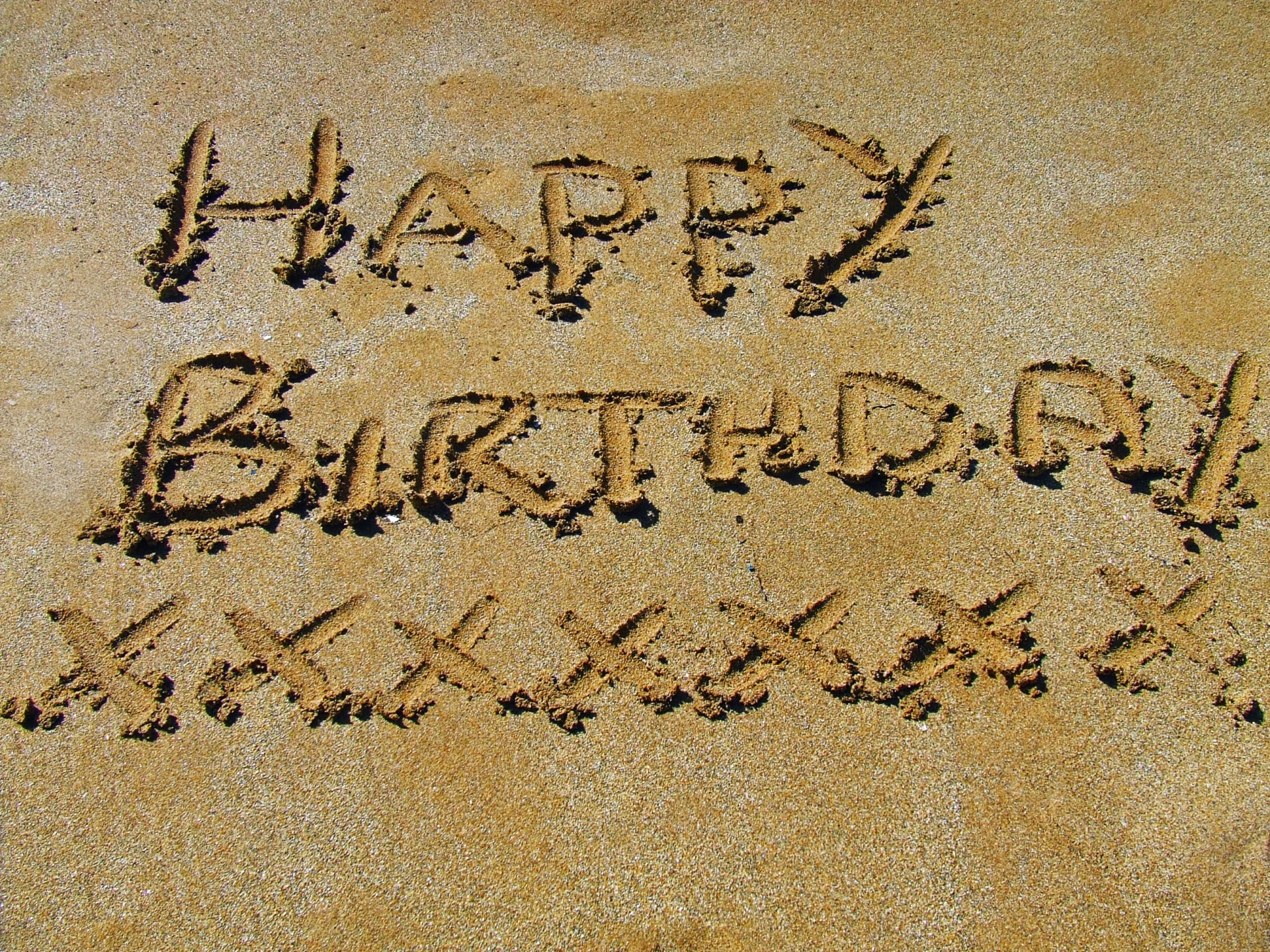Happy birthday written in the sand