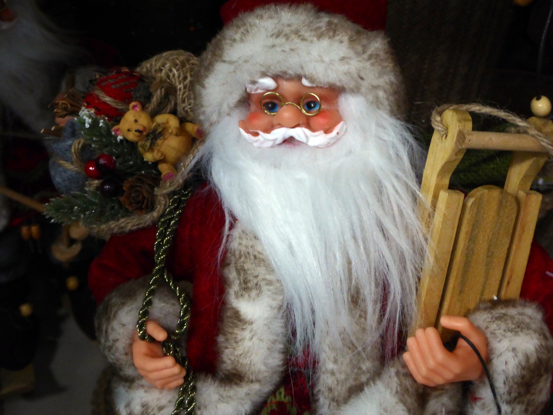 Christmas decoration of Santa Claus with bag of toys hoisted over his shoulder and carrying a sled in other arm