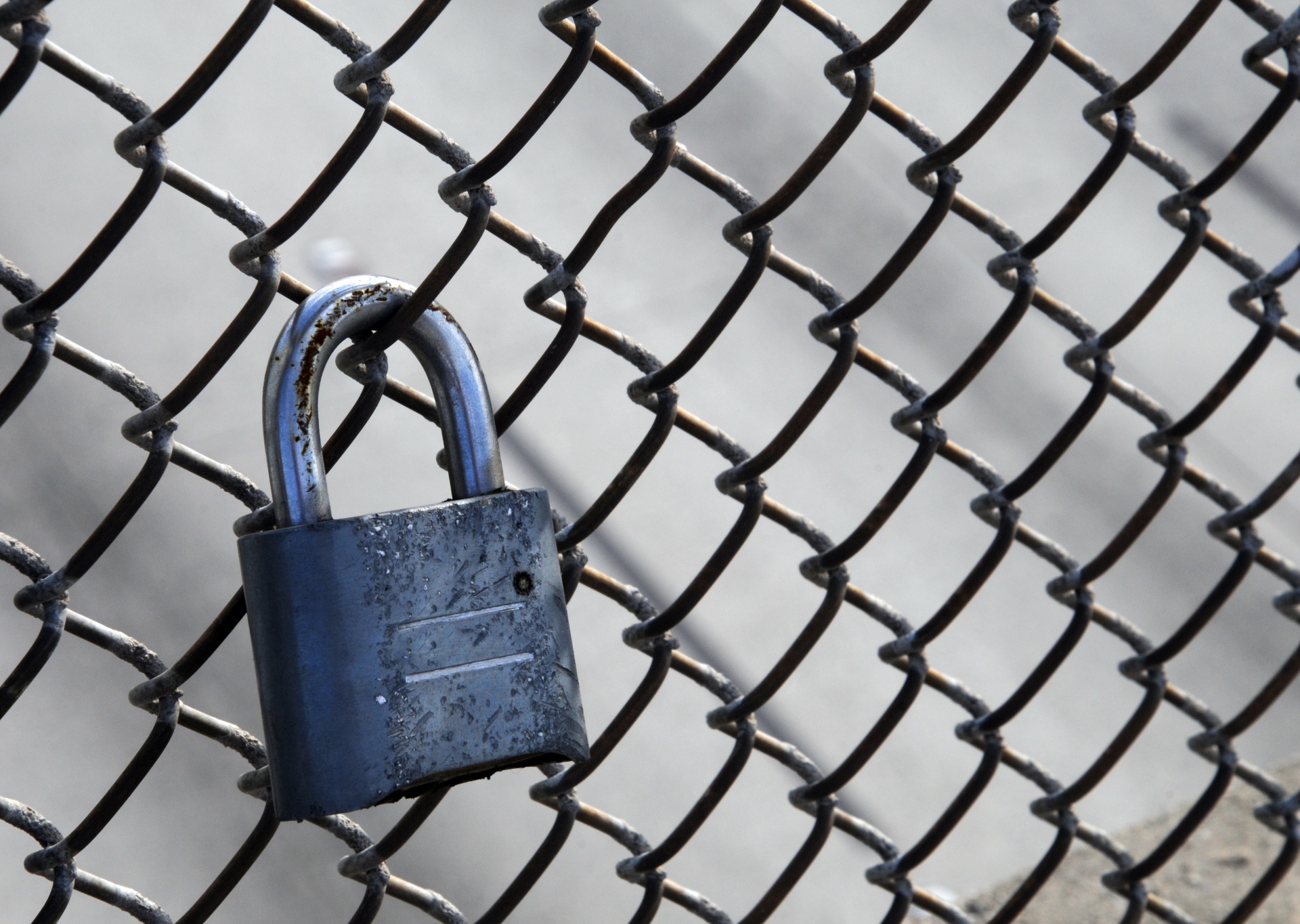 close up of a padlock hanging on a chain link fence