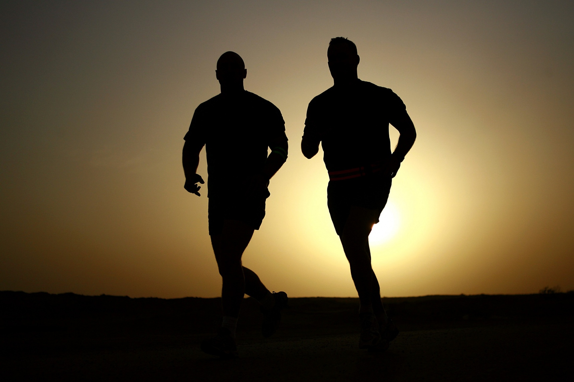 Silhouettes of men jogging at sunset