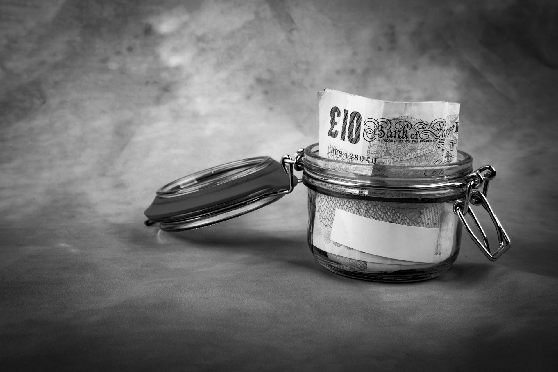 Collecting money for travel. Glass tin as moneybox with cash savings on the old background. White empty paper for text.