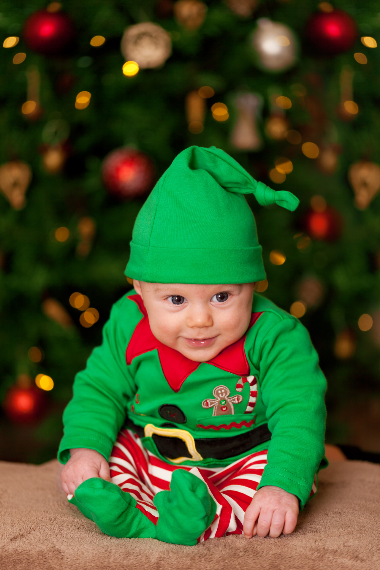 cute baby elf in front of a Christmas tree
