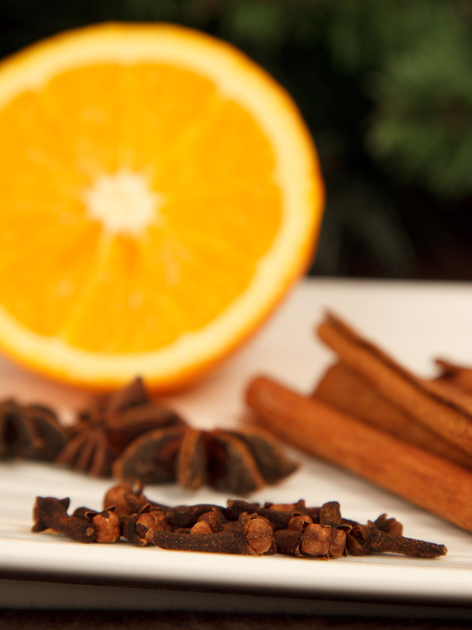 cloves on the plate with cinammon and orange blurred on the background