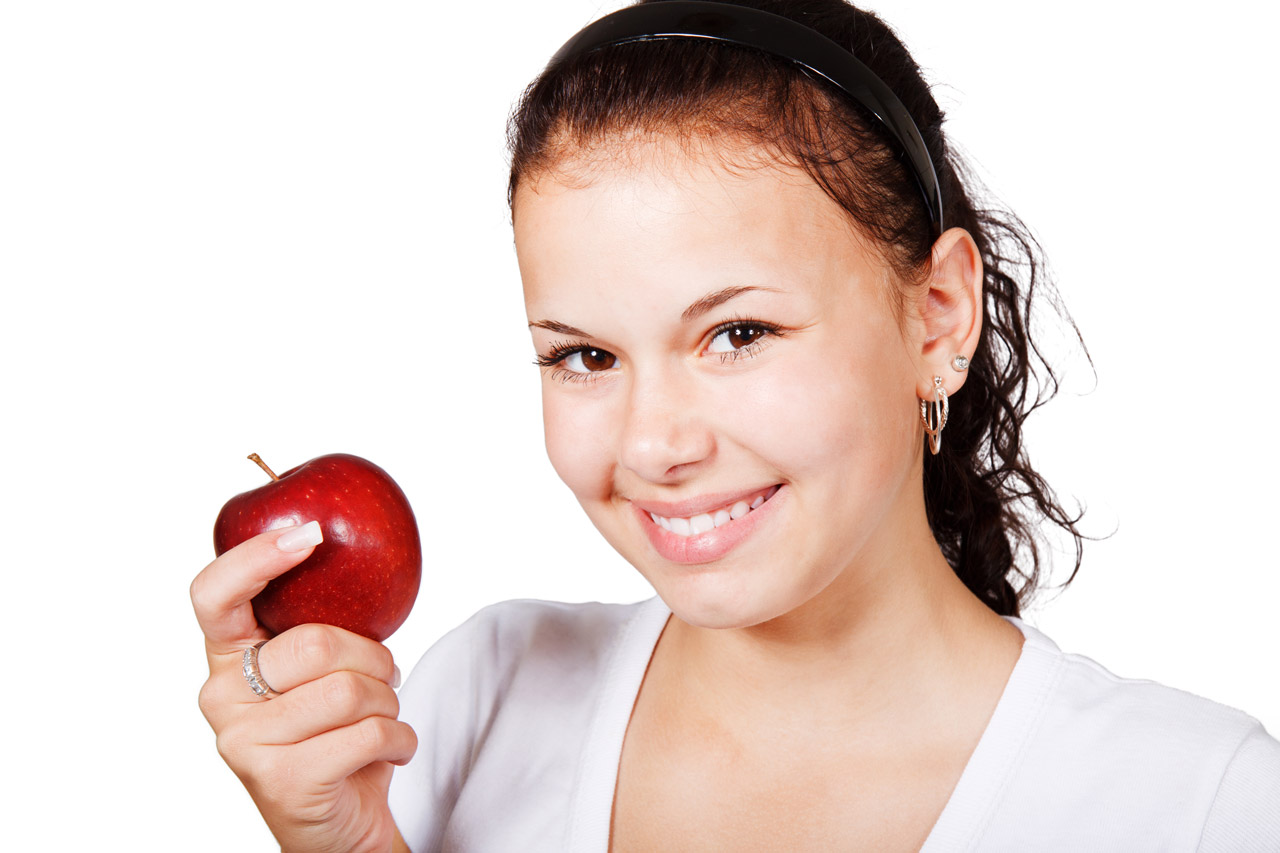 young woman smiling holding red apple isolated on white background