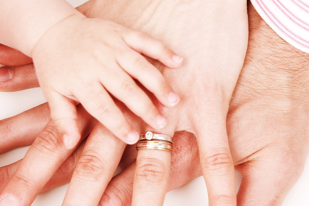 hands of father, mother and their baby on each other