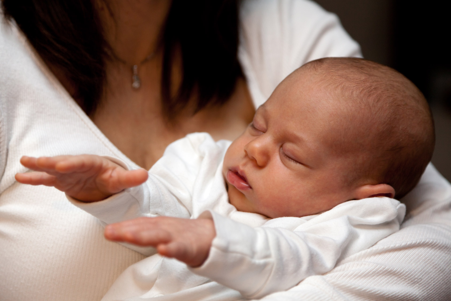young baby sleeping with his hands in the air