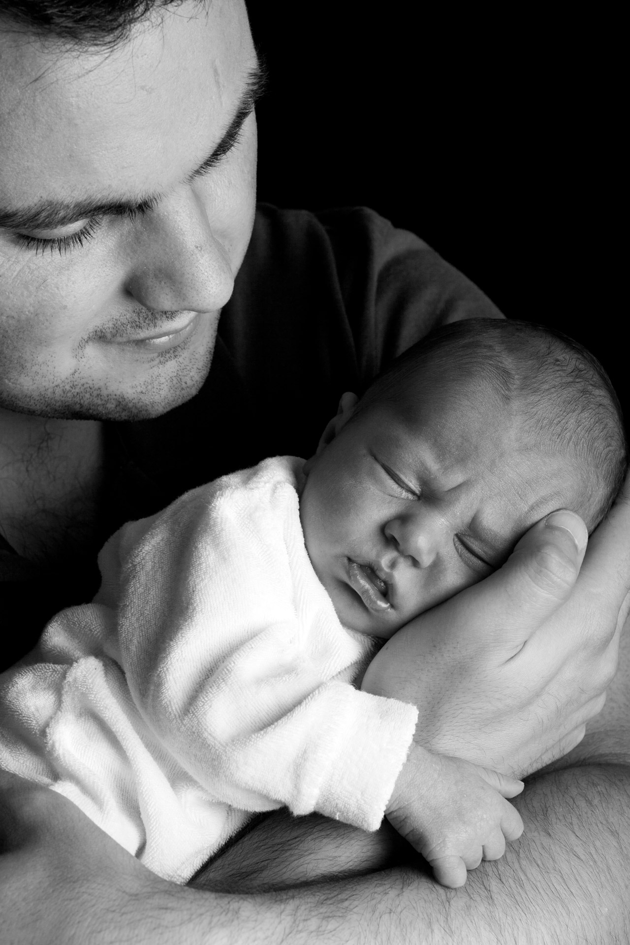 daddy holding a newborn in black and white