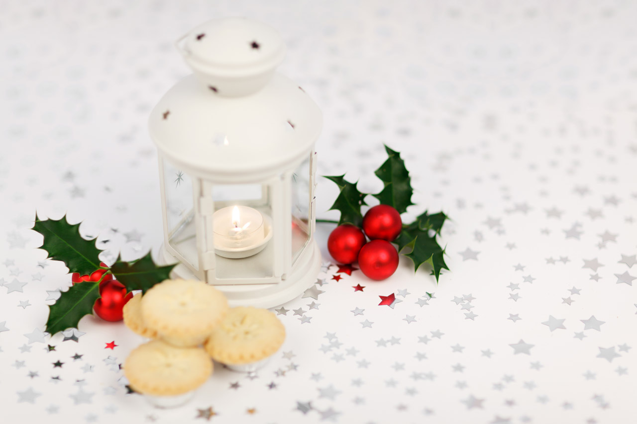lantern, holly and mince pies on starry background