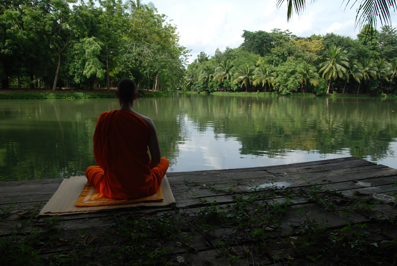A monk is meditating by the lake in one of the most beautiful monastery in Thailand