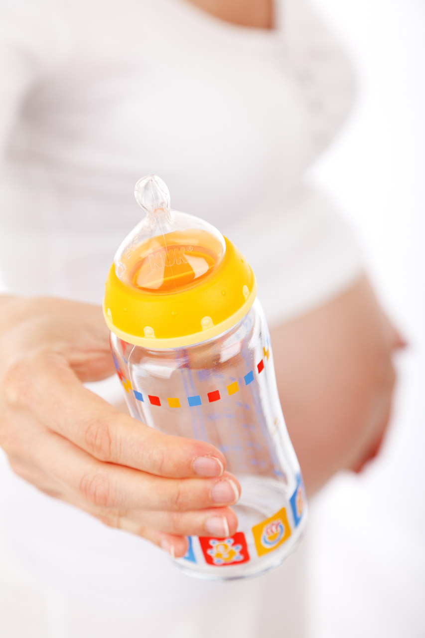 mother to be with a colorful glass feeding bottle