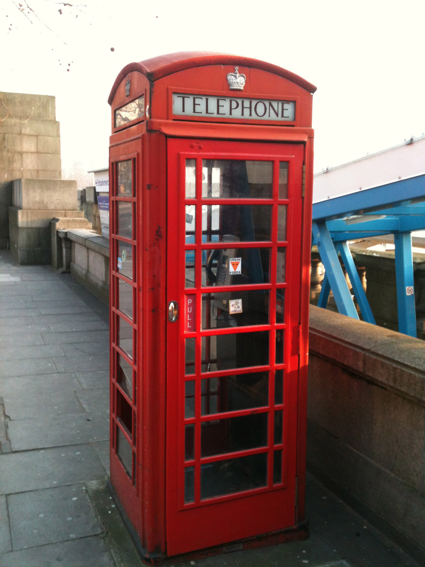 A picture of a red telephone box, outside  of Charing Cross Underground station by the river thames
