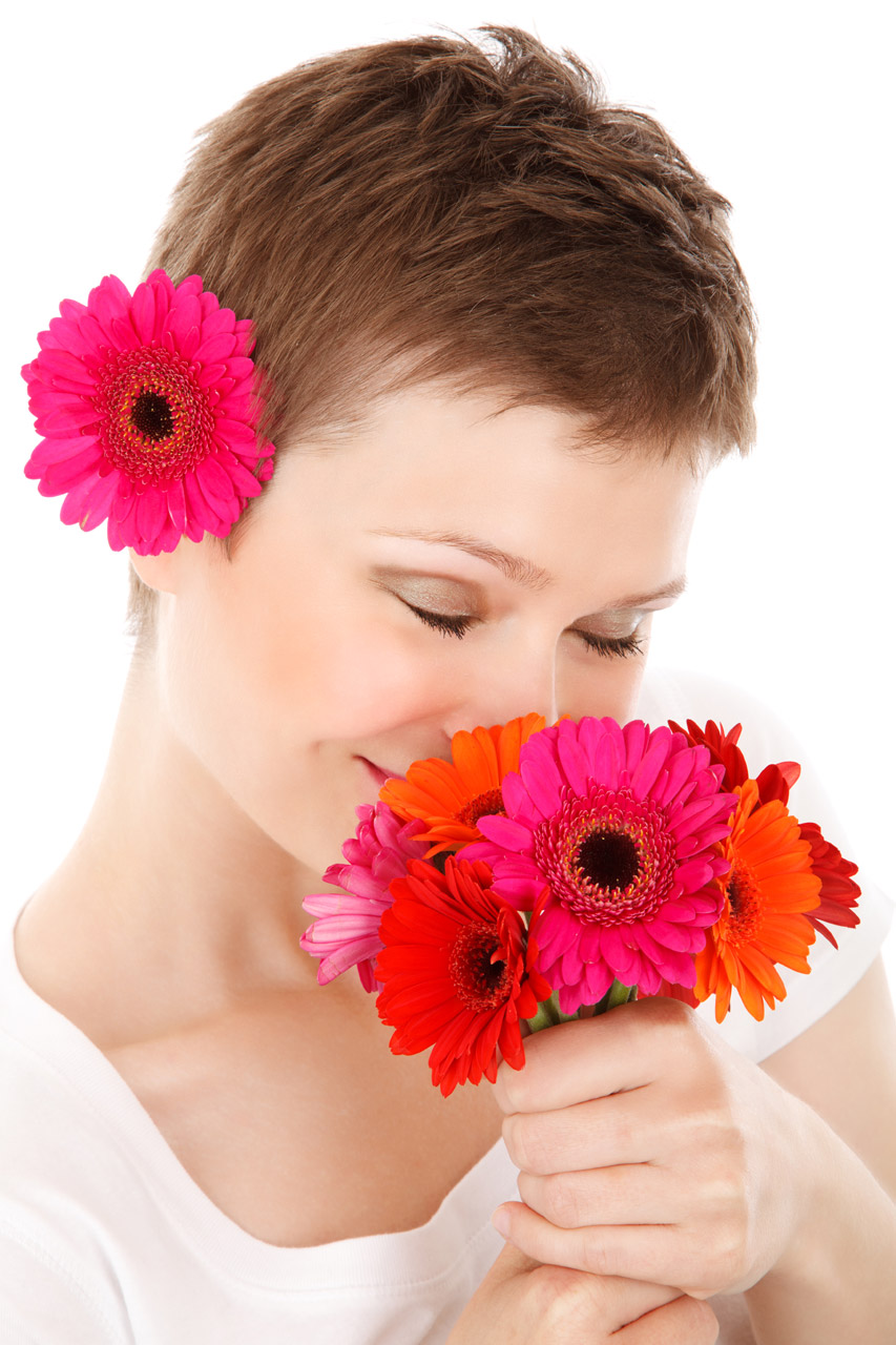 young woman smelling bouquet of colorful flowers isolated on white background