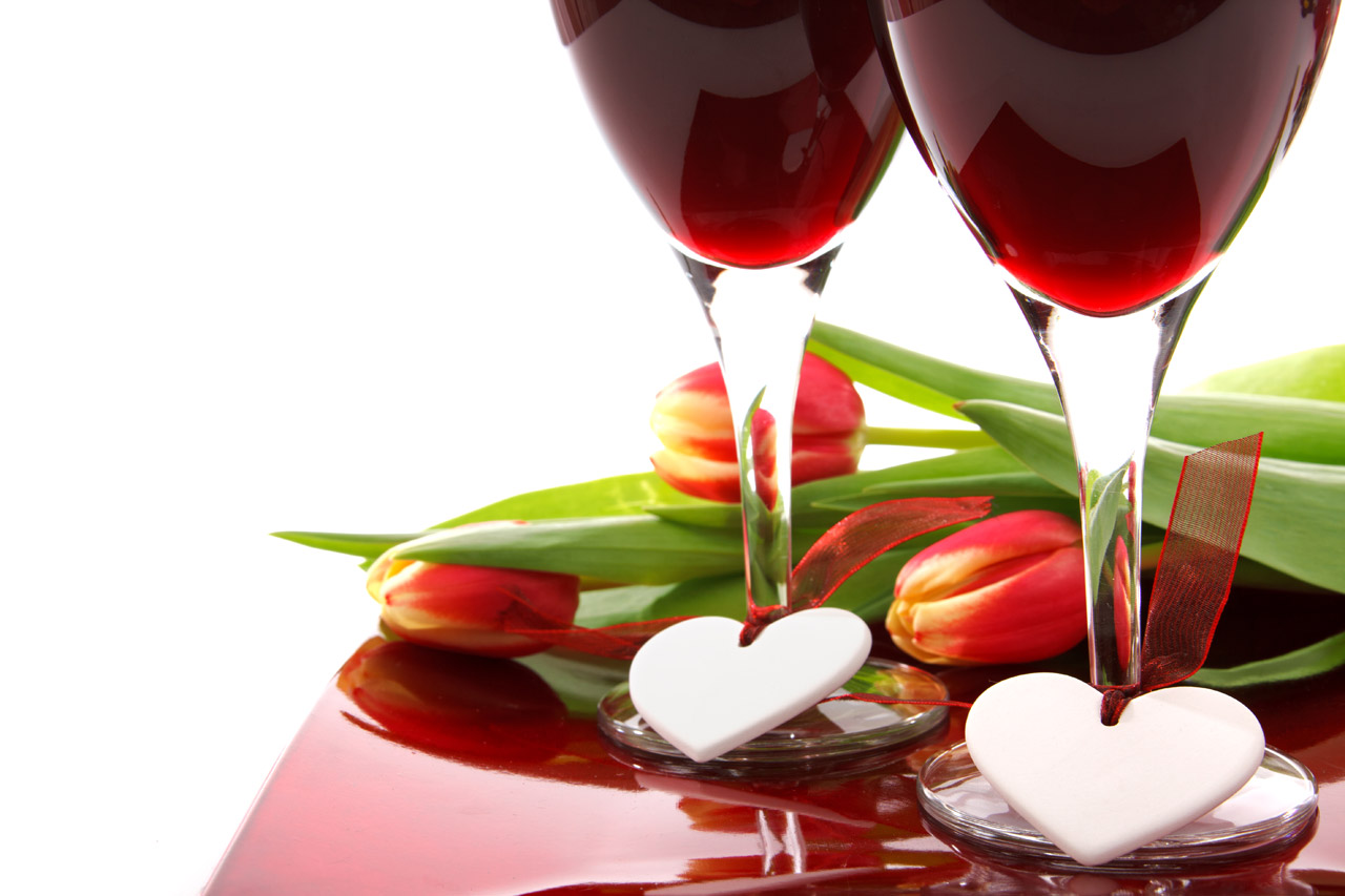 valentine decoration with two glasses of wine, white hearts and colorful tulips on white background