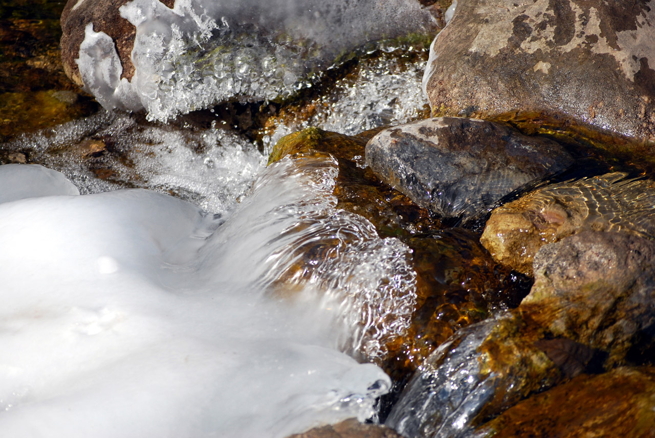 mountain stream flowing over rocks forming ice build up