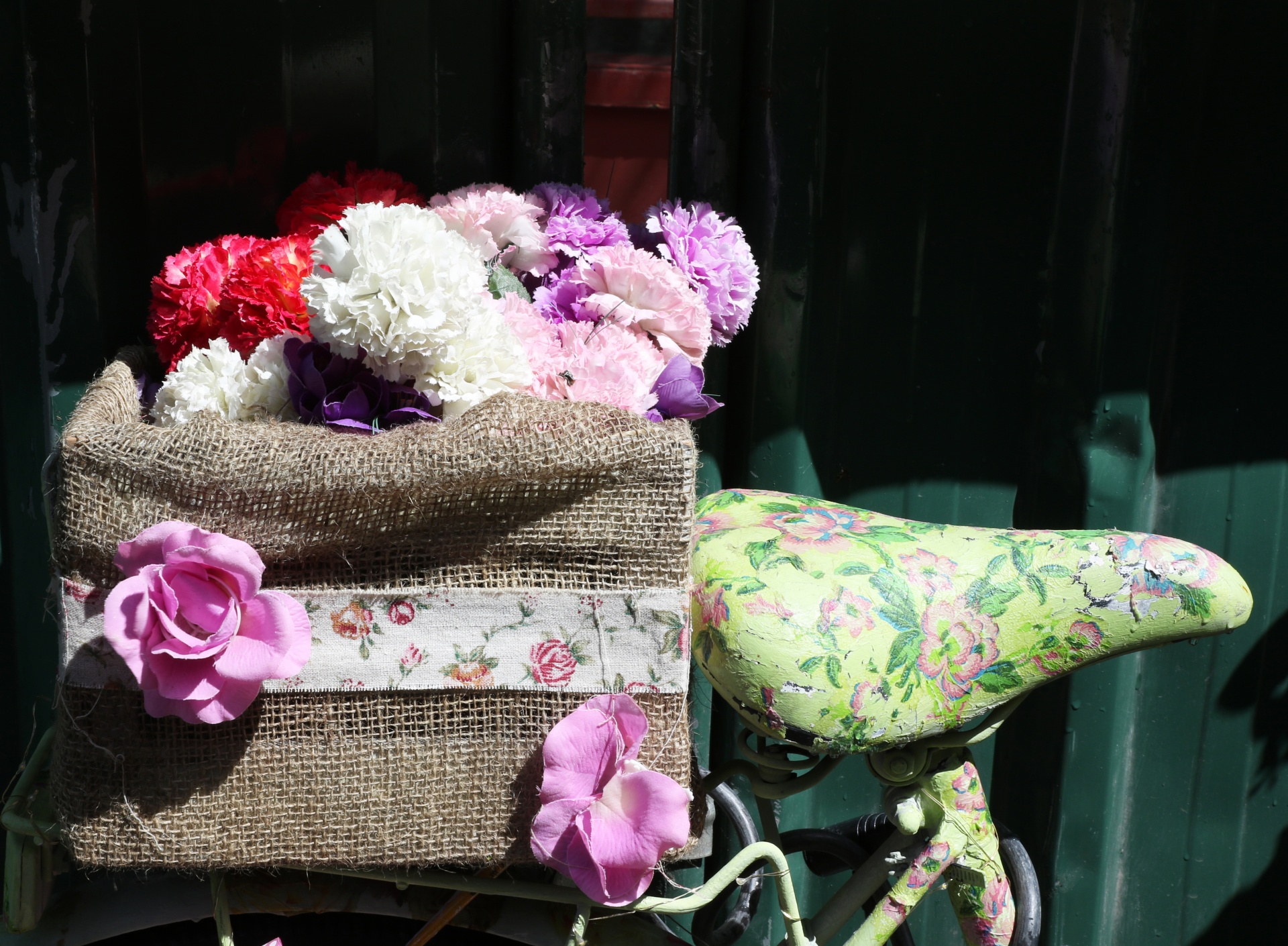 Close-up of a floral bicycle saddle and box of carnation flowers