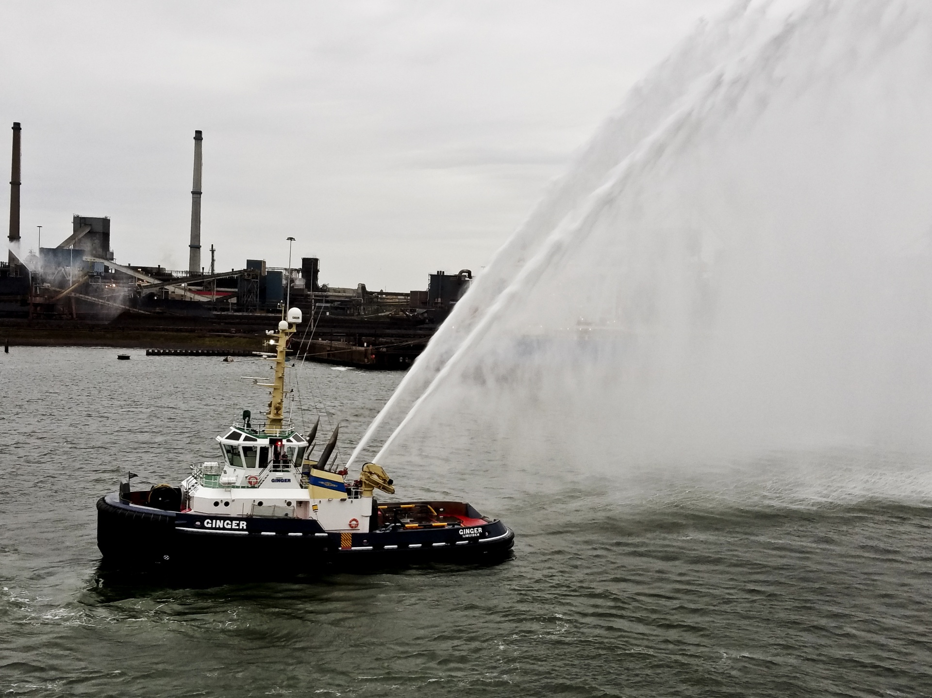 water shooting from a tug boat saluting departing ship