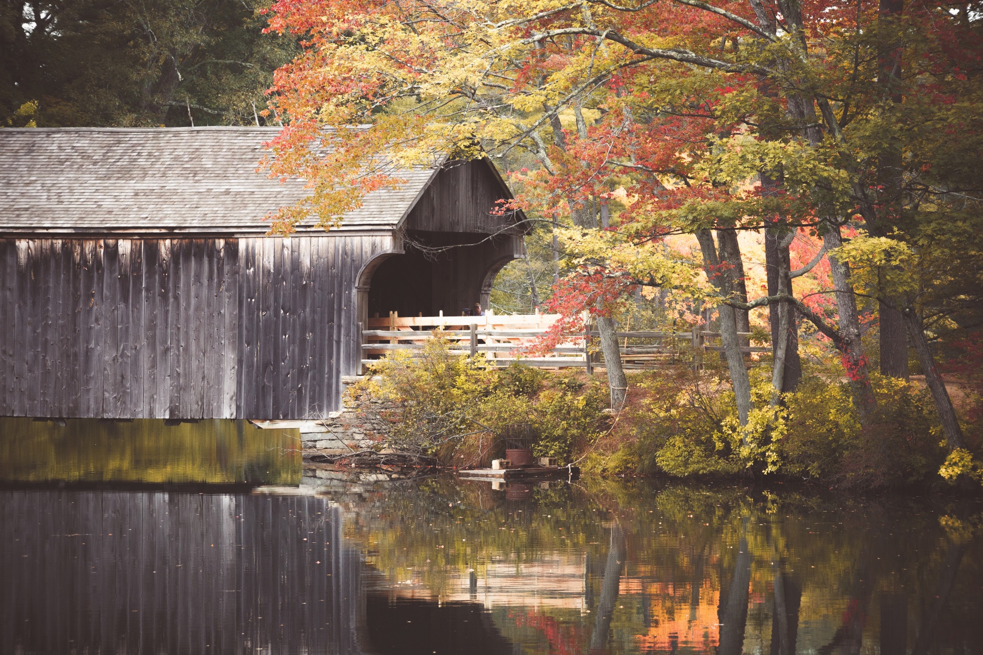 Old wooden covered bridge with the pond reflection in autumn