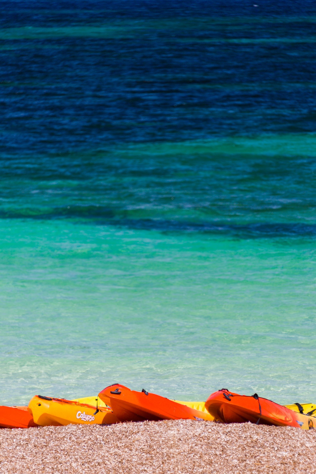 Colorful kayaks on the beach with sea in the background