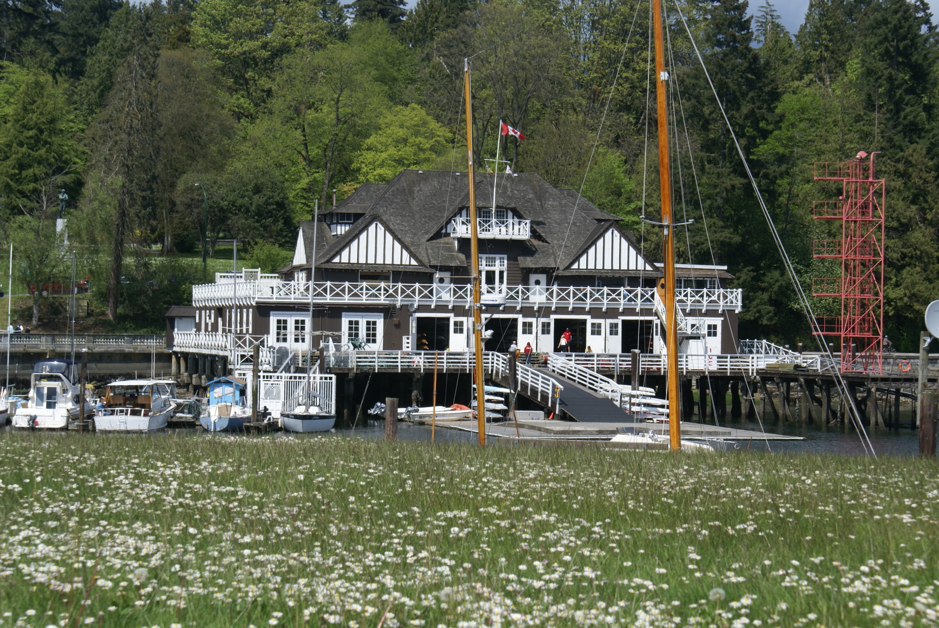 Historic Royal Yacht Club at Stanley Park Vancouver with yachts moored in front and leafy trees behind.