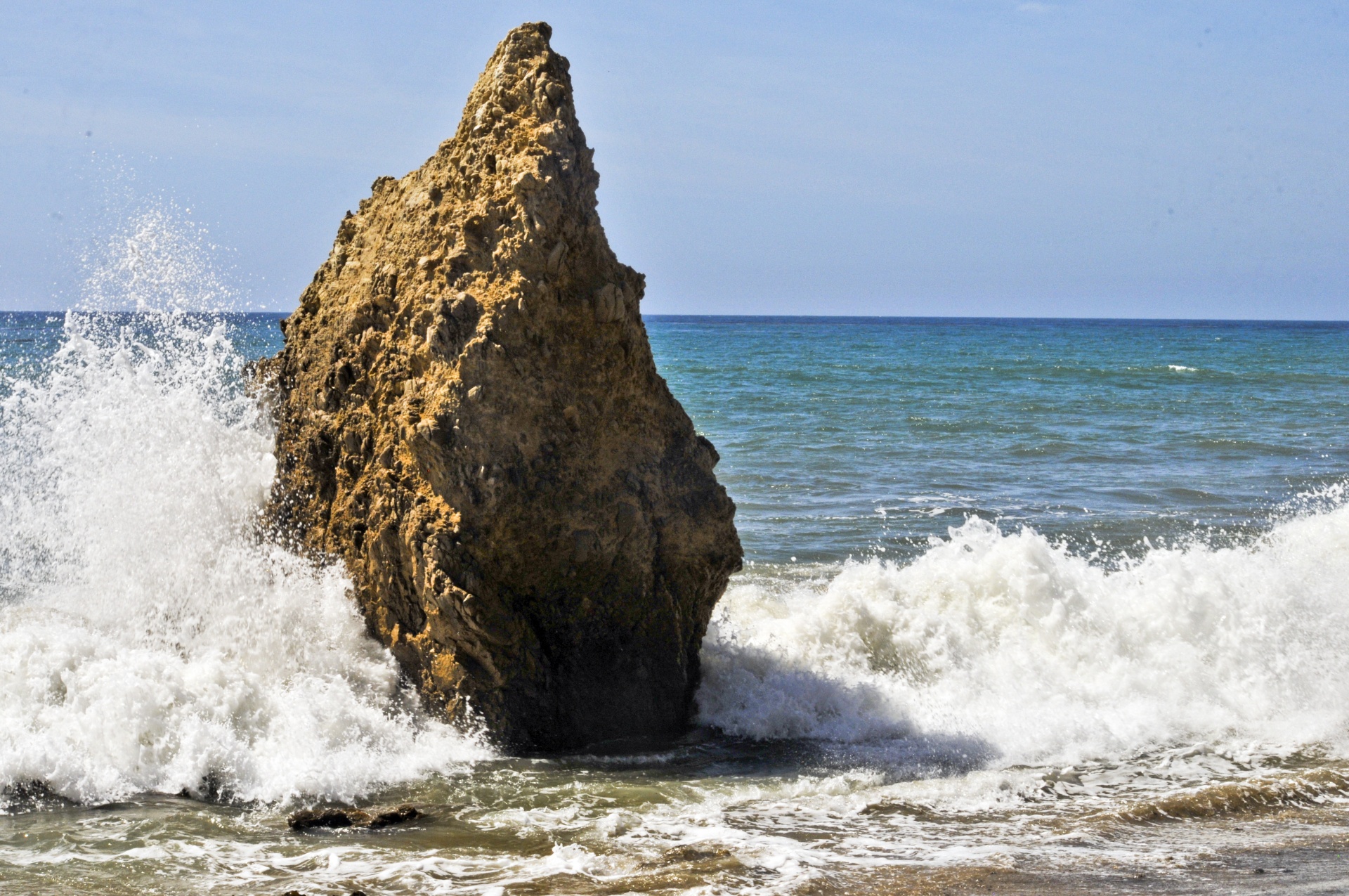 large rock with waves crashing around it