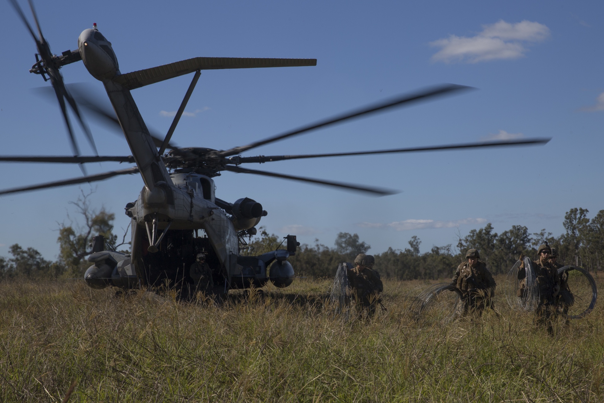 Marines with Kilo Company, Battalion Landing Team, 3rd Battalion, 5th Marines, carry concertina wire off of a CH-53E Super Stallion helicopter during an embassy reinforcement exercise a part of Certification Exercise at Shoalwater Bay Training Area,