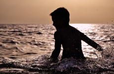 Toddler Splashing In The Sea By Sun
