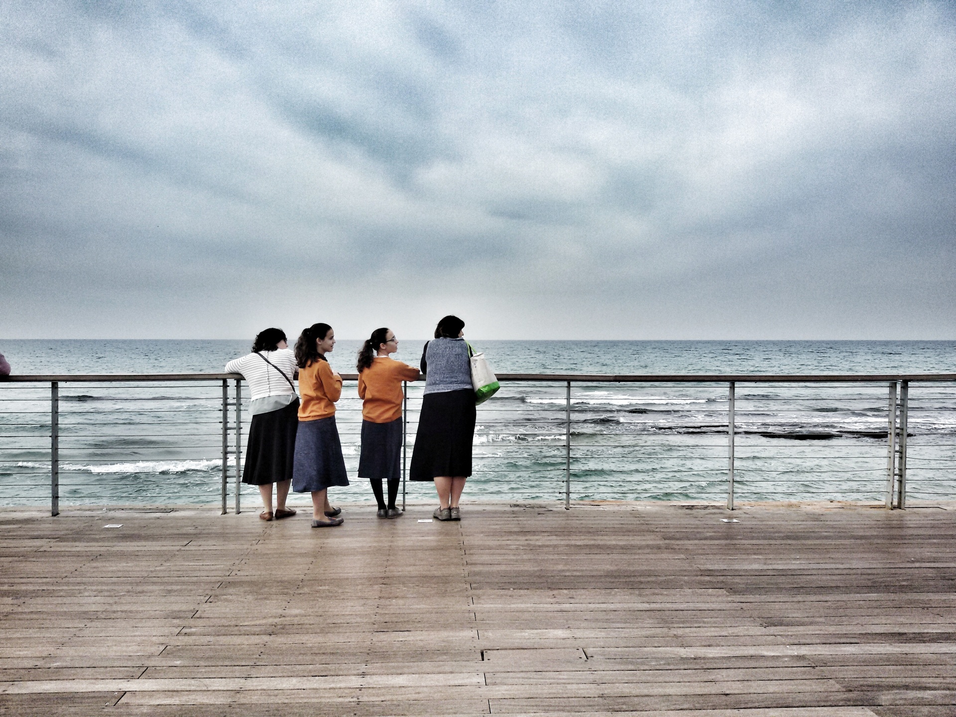 Girls at the seaside under a dark and cloudy sky