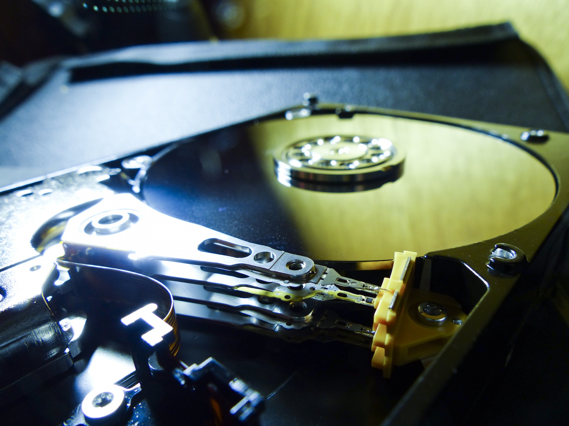 Golden disc and arm of a computer hard drive. Metal reflects light.