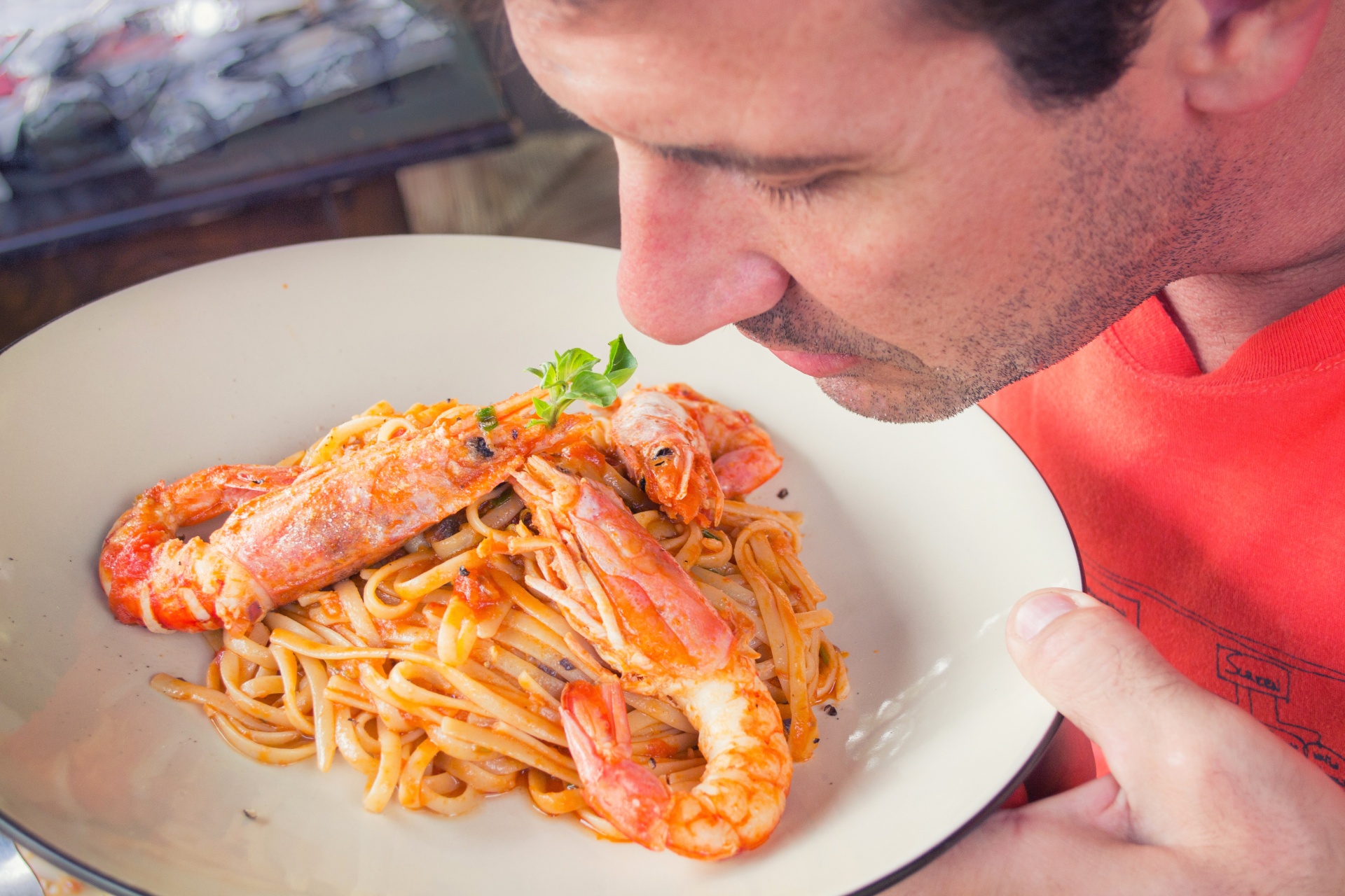 Man Smelling Plate Of Shrimps Pasta
